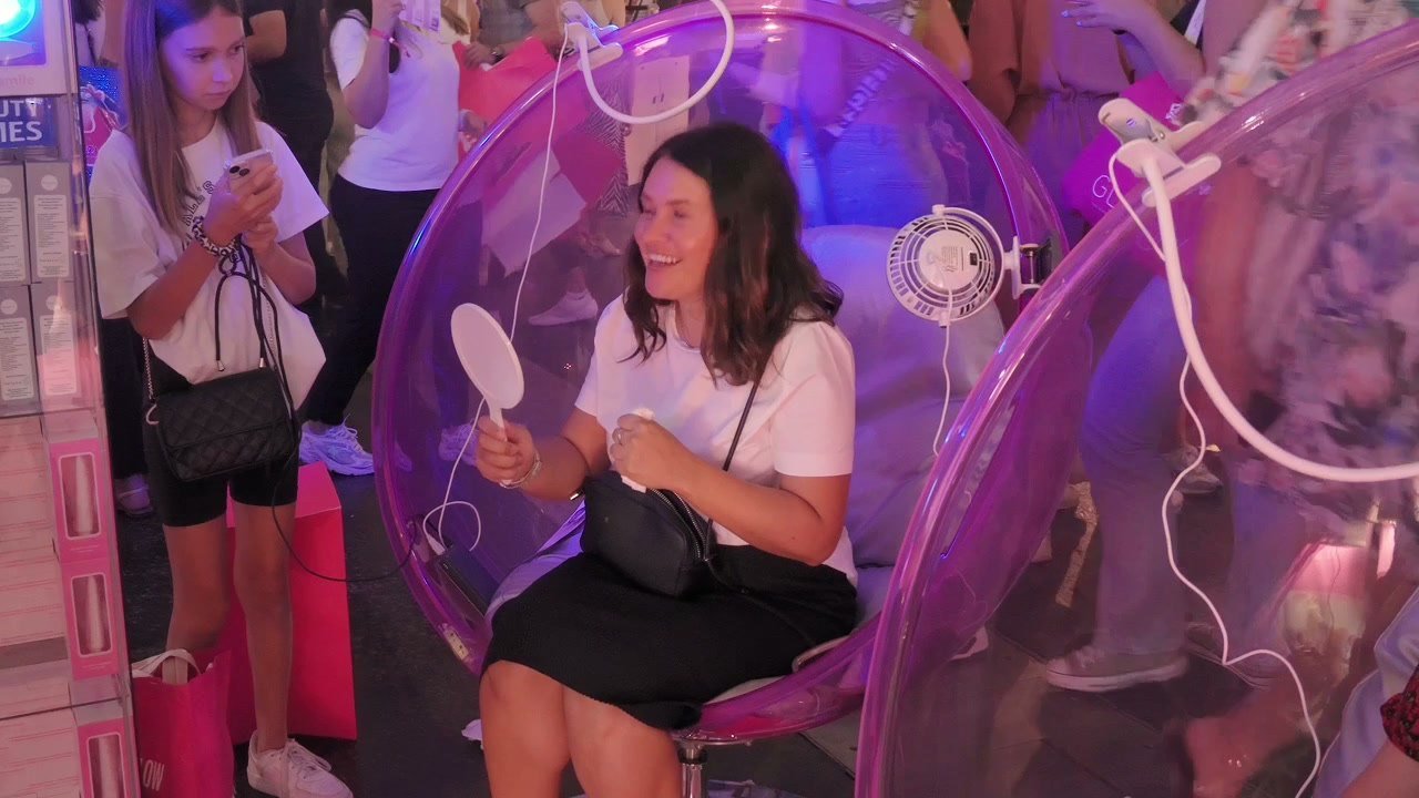 Cliente souriante dans un fauteuil-bulle OnlySmile, miroir à la main